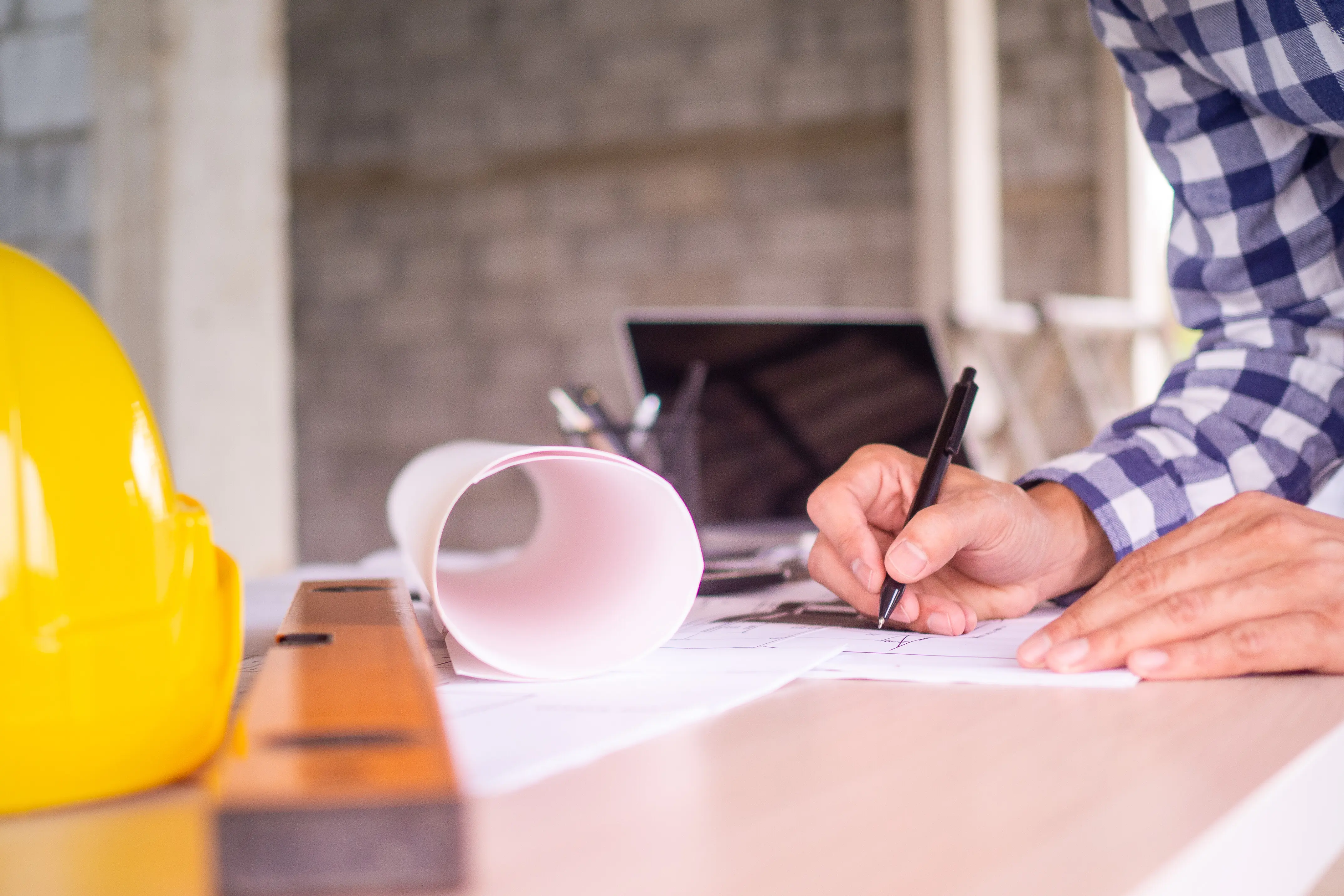 Man’s hand working—an architect sketching a project on a blueprint at a construction site. Concept of architect and engineer on an office desk construction project banner.