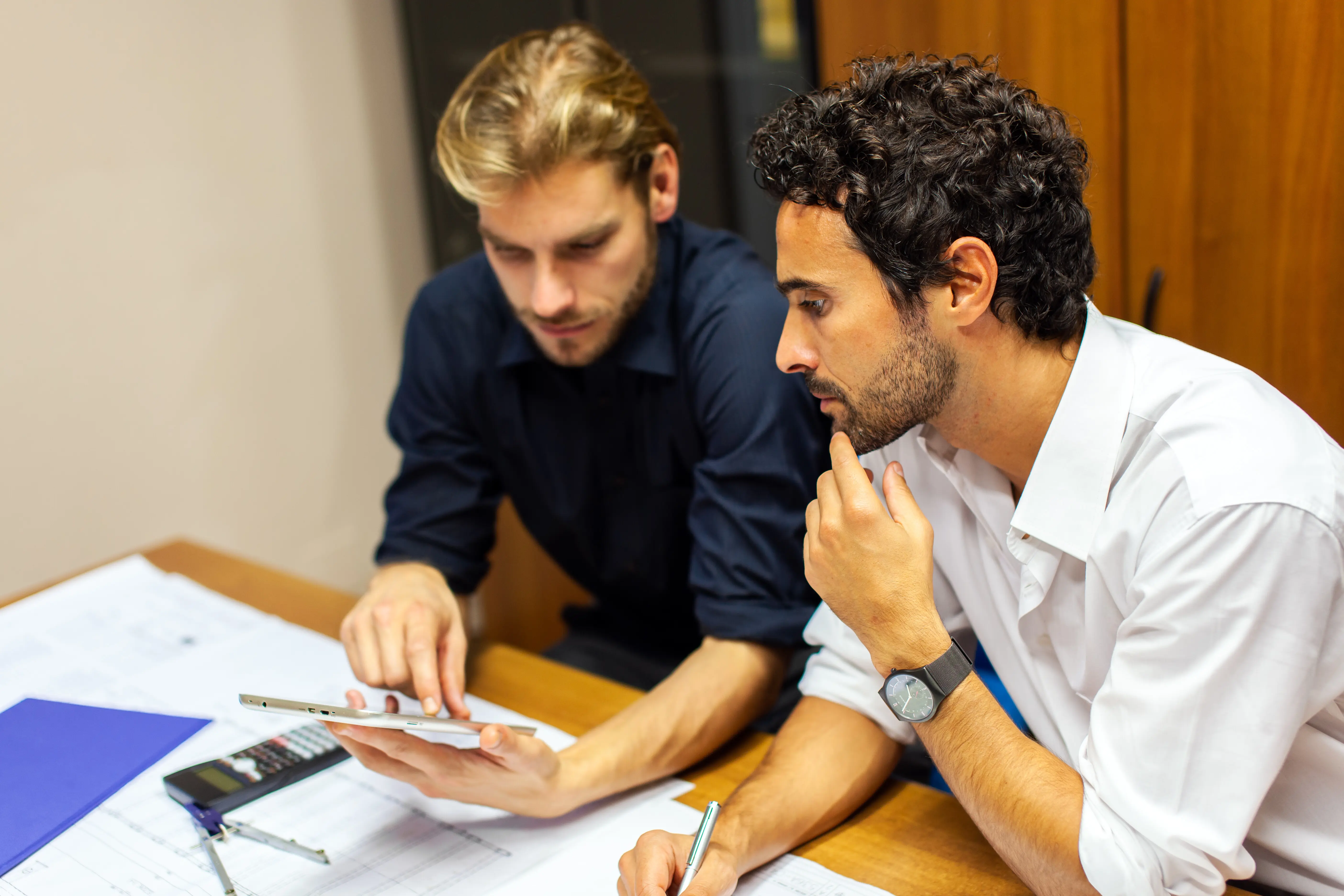 Two businessmen collaborating and performing calculations